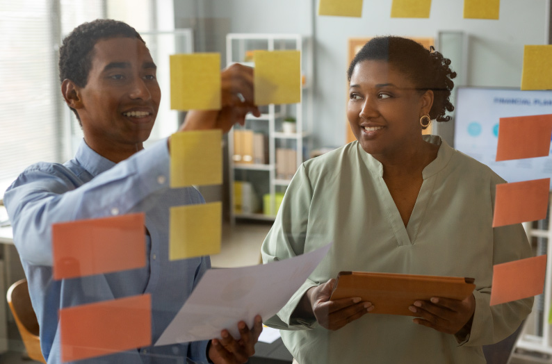 Business consultants in Ghana helping SMEs improve profitability. A Ghanaian business consultant reviewing financial performance, operating costs, and growth plans with an SME owner.